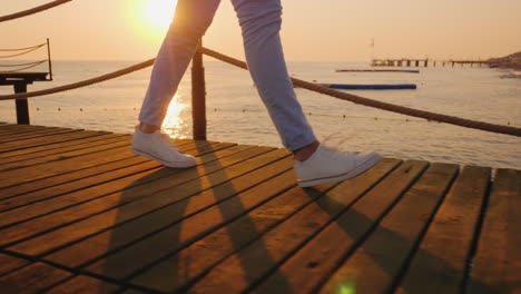 the woman walks along the pier in the early morning in the frame only the legs can be seen steadicam