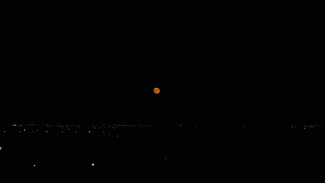 Imágenes-Nocturnas-De-Luna-Llena-Naranja-Sobre-El-Paisaje-Urbano,-Cerca-Del-Aeropuerto-Internacional-De-Atenas-4k