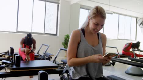 mujer usando teléfono móvil en el estudio de fitness 4k