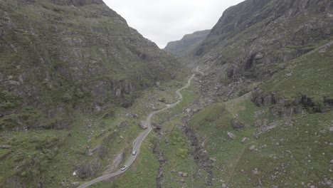 winding road through towering mountain valley at gap of dunloe in kerry county, ireland