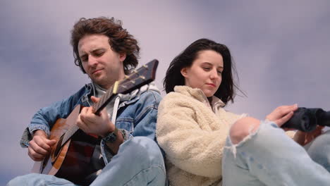 a young boy plays the guitar and a young girl looks around with a pair of binoculars on the roof of a caravan 2