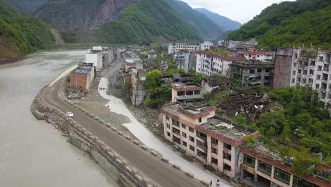 aerial shot of a ruined area along a river lidung county, sichuan province, china, after the earthquake