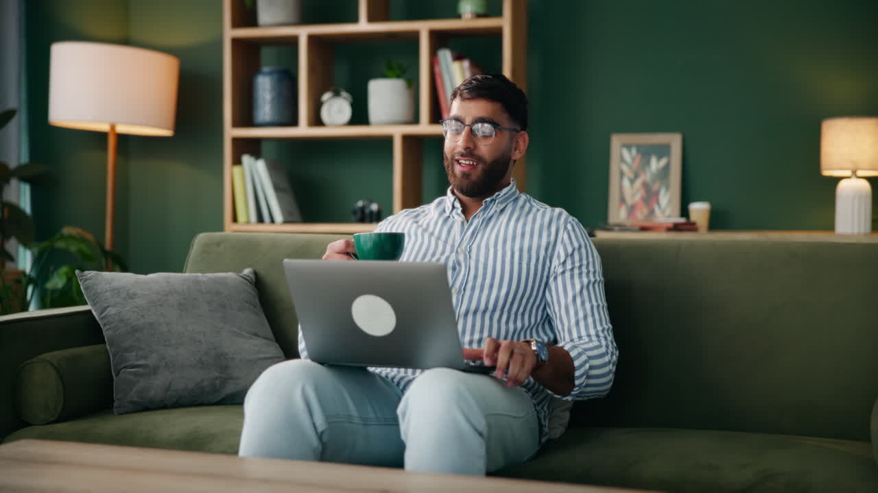 Man using laptop and drinking coffee on couch
