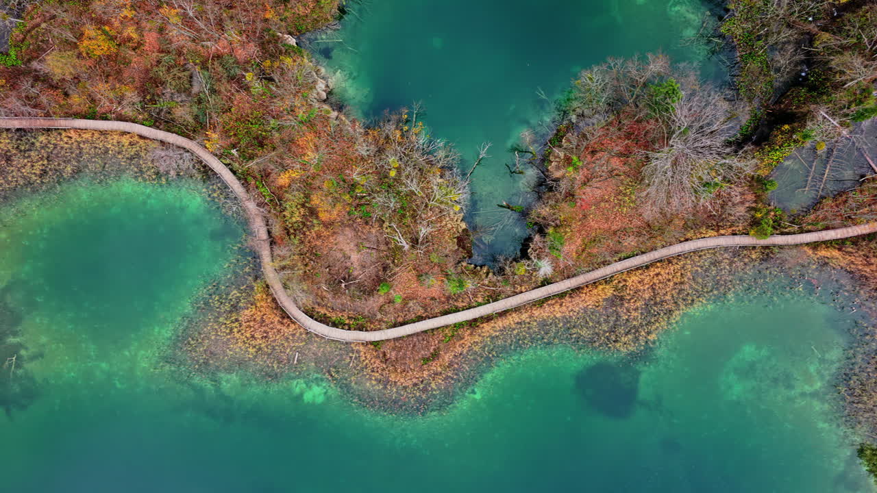 Aerial drone view of the winding wooden walkways built above turquoise shallows and wetlands at Plitvice Lakes, Croatia