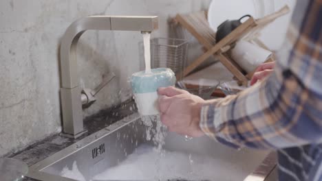 Hands-of-caucasian-man-washing-dishes-in-kitchen,-slow-motion