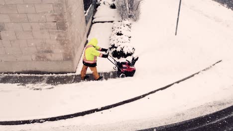 unrecognisable operator using snowblower to clean driveway when snowing, brampton, ontario, canada