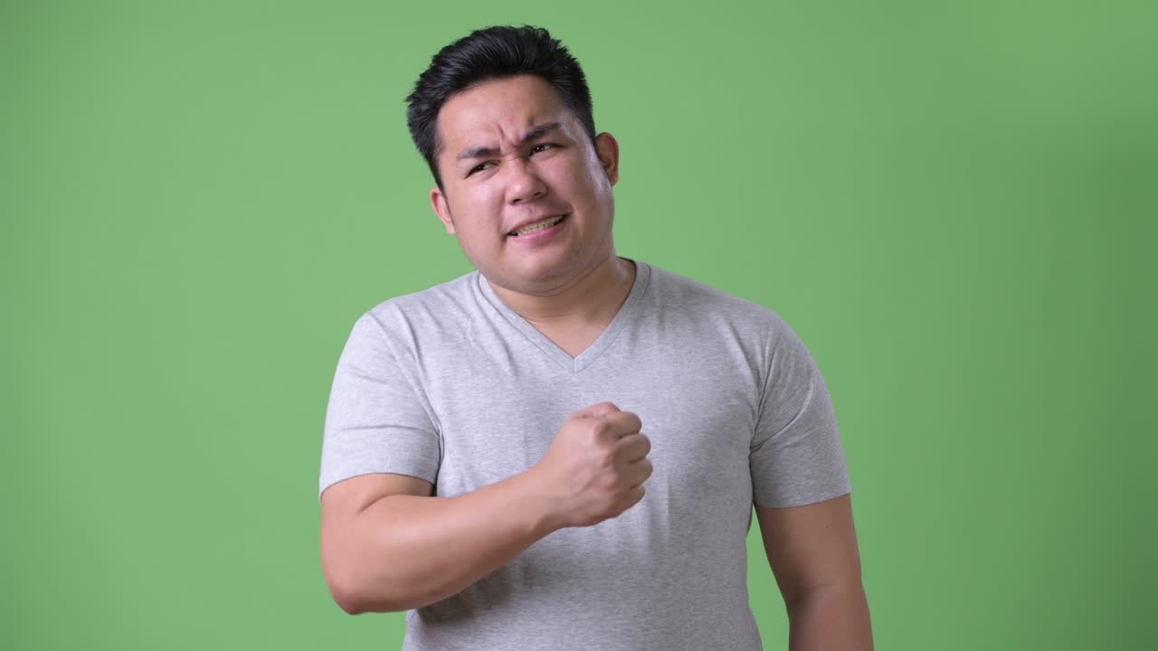 초록색 배경에 젊은 잘생긴 과체중 아시아인