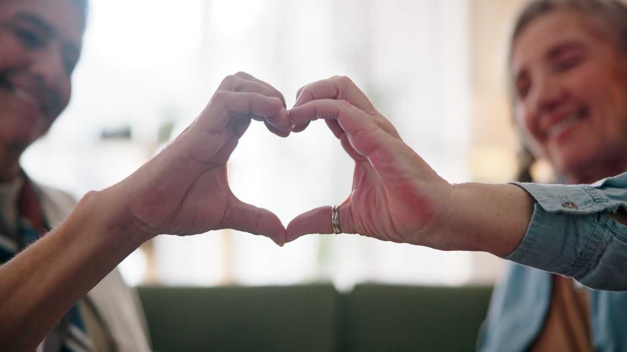 두 명의 행복한 노인들이 손으로 심장 모양을 만들고 있습니다.