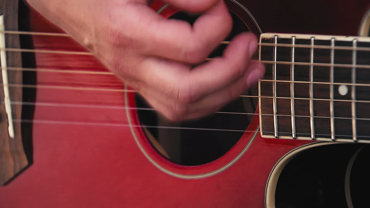 Close shot of a woman playing a red guitar outside.