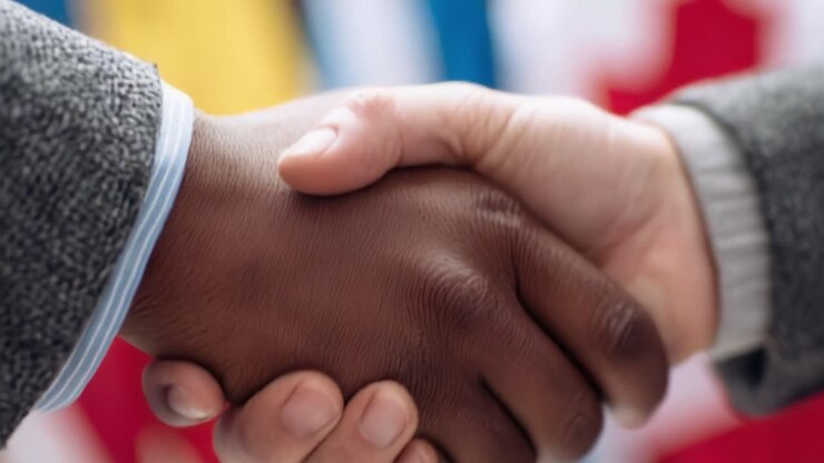 Close-up de um aperto de mão que simboliza parceria, união e colaboração em meio a um plano de fundo colorido de diversas culturas e ideias