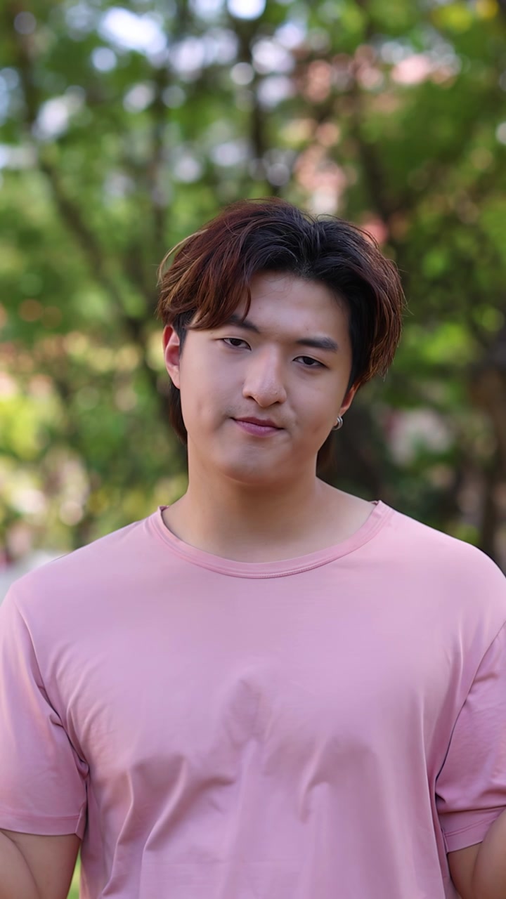 ชายหนุ่มชาวเอเชียยักไหล่และดูสับสนขณะยืนอยู่กลางแจ้งในเวลากลางวันที่มีแสงธรรมชาติ