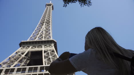 Woman taking a photo of the Eiffel Tower in Paris