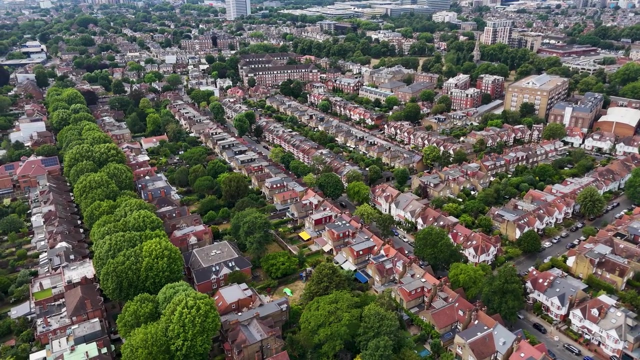 Una fitta griglia di strade a schiera e alberi secolari riempie un sobborgo di Londra ovest, con lo skyline della città all'orizzonte lontano