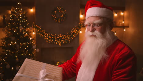 santa claus is holding and shaking a large beautiful box with a present for an obedient child for a happy christmas. looks at the camera and smiles. medium shot. high quality 4k footage