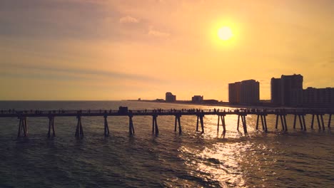 Eine-Atemberaubende-Drohnenaufnahme-Des-Längsten-Piers-In-Florida-Bei-Sonnenuntergang-Mit-Goldenen-Farben