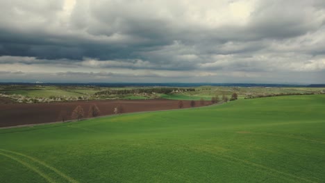 drone flying over a green hill flies to the top and reveals a picturesque landscape with storm clouds gathering above