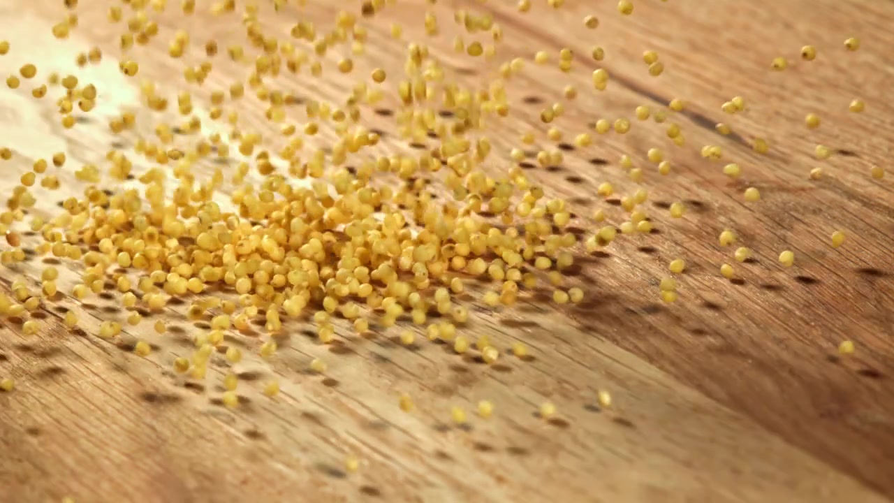 Zeitlupe von Hirsekörnern, die auf einen Holztisch fallen