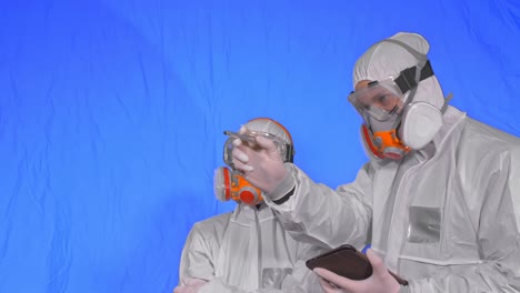 scientist virologist in respirator makes write in an tablet computer with stylus. man and woman wearing protective medical mask. chroma key blue.