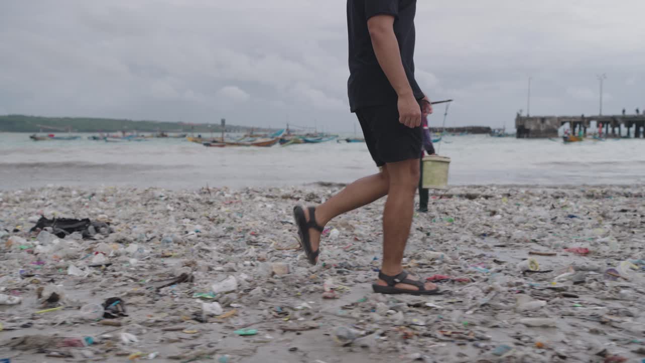 Man Walking Through Plastic-Covered Beach