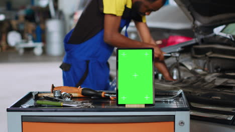 Car mechanic next to green screen tablet
