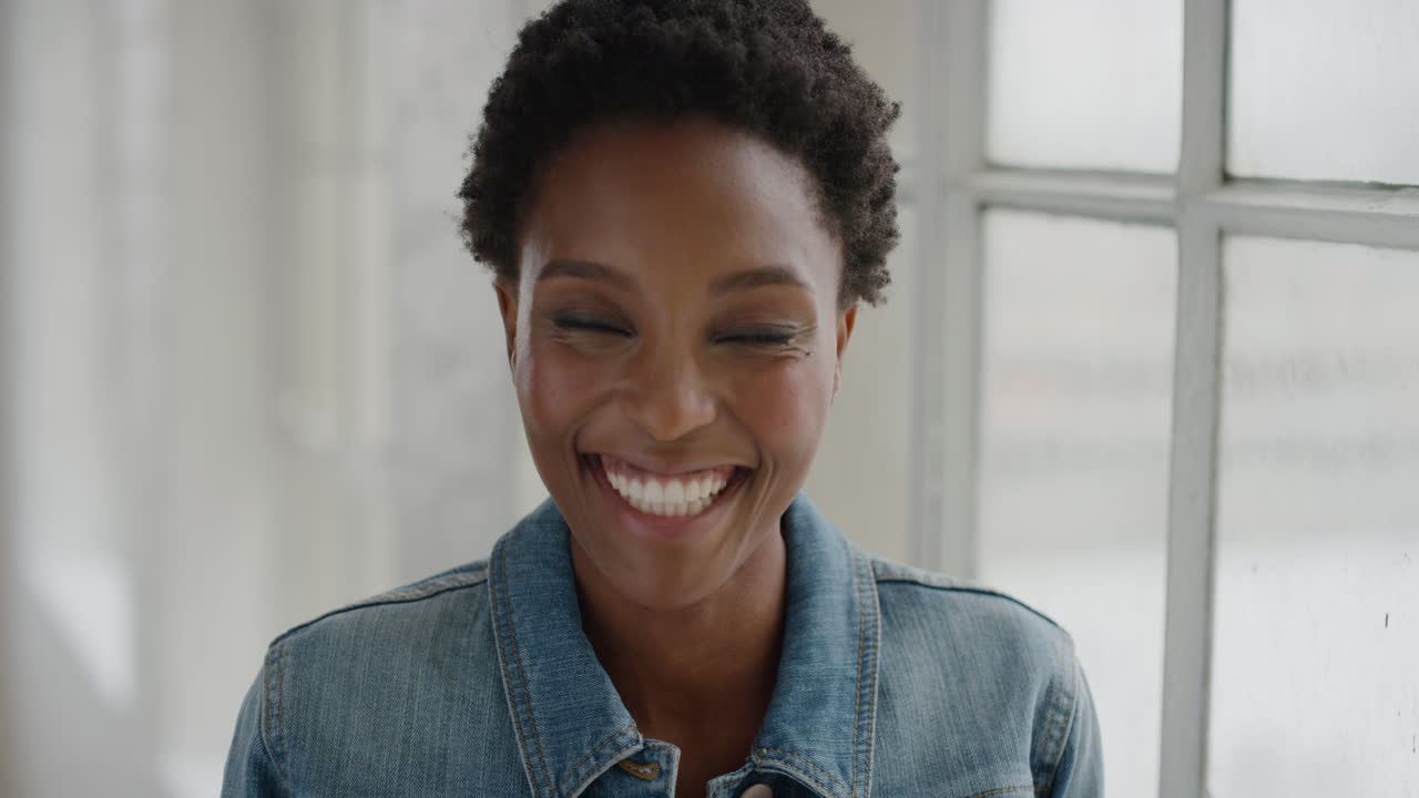 close up portrait of beautiful african american woman laughing happy enjoying lifestyle success looking at camera wearing denim jacket