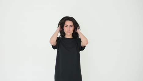 young woman adjusting her hair and posing in a black t-shirt against a white background