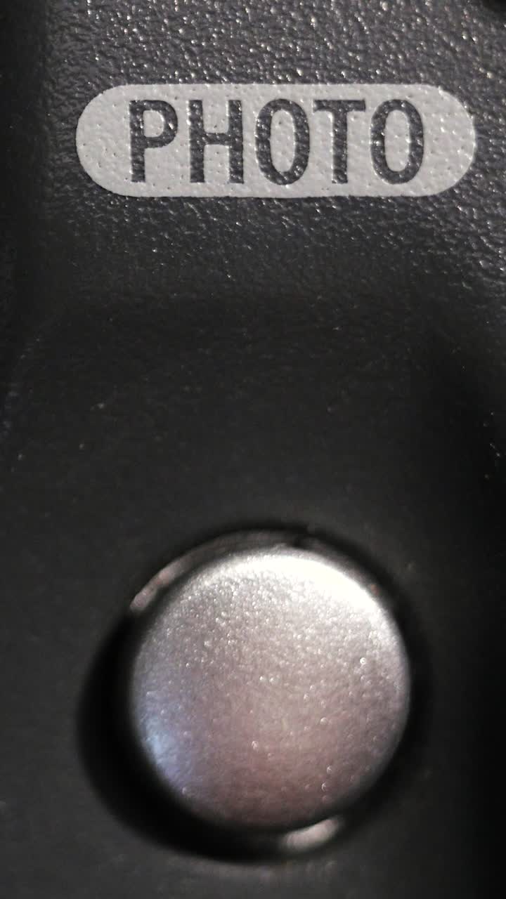Vertical macro close up of photo button pressed on dark grey device