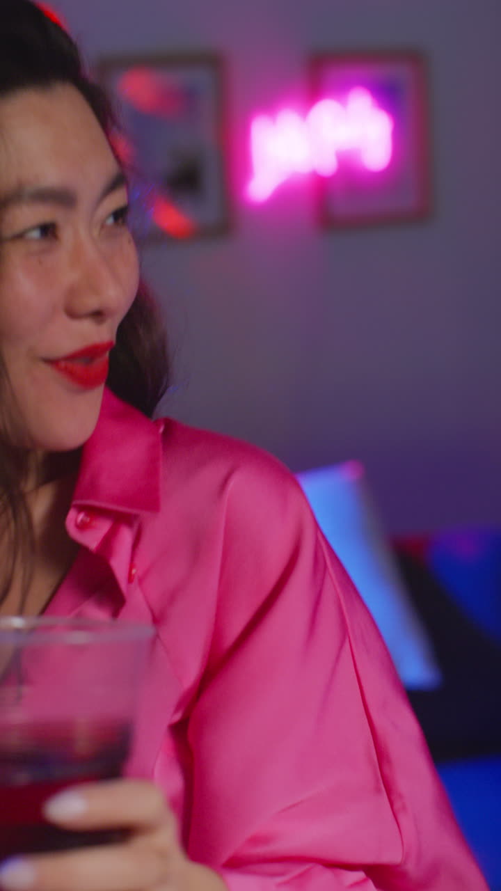 Vertikal video af kvinde, der hygger sig, danser og drikker alkohol til en hjemmefest.