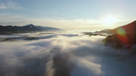 drone shot van een ongelooflijk landschap bedekt onder de mist met omliggende bergen in de ochtend in de winter in slovenië vastgelegd in 4k, drone vooruit