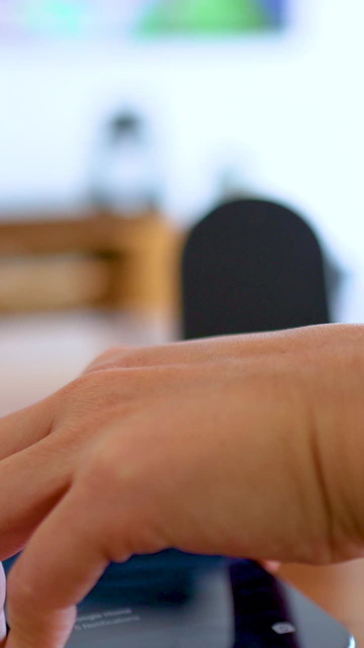 Una persona posiziona uno smartphone su un caricabatterie wireless in una stanza ben illuminata, evidenziando la tecnologia moderna e la comodità.