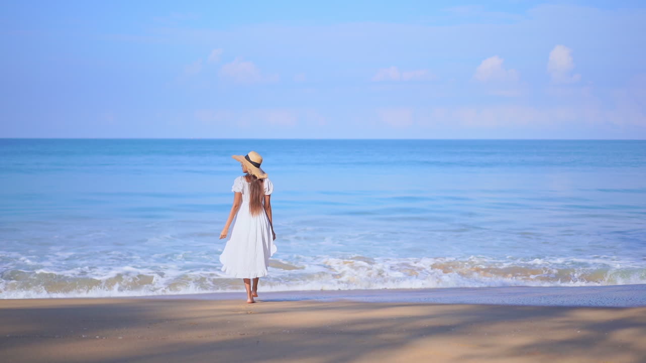 해변을 걷고 하늘로 팔을 올리는 여성의 뒷모습