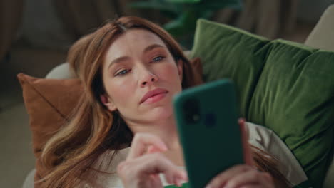 lazy girl scrolling cellphone lying on home couch close up. calm woman watching