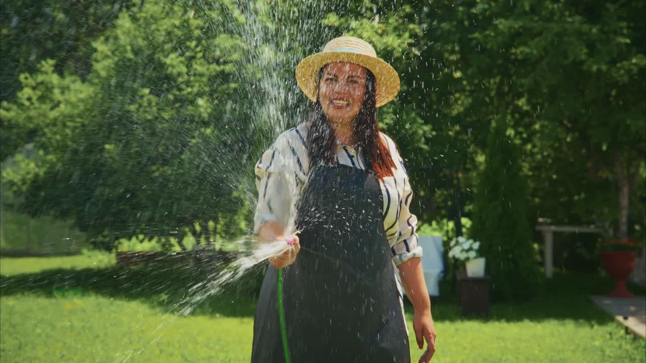 Woman in straw hat watering plants in a lush garden, showcasing vibrant greenery and joyful atmosphere