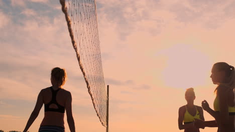 Gruppe-Junger-Mädchen,-Die-Bei-Sonnenuntergang-Oder-Sonnenaufgang-Beachvolleyball-Spielen