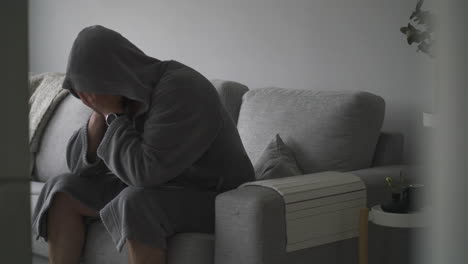 Troubled-Sad-Caucasian-Male-in-a-Robe-sits-in-sofa-at-home-showing-emotional-feelings-of-sadness-and-despair