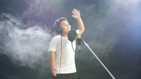 young boy singing into a microphone in a recording studio