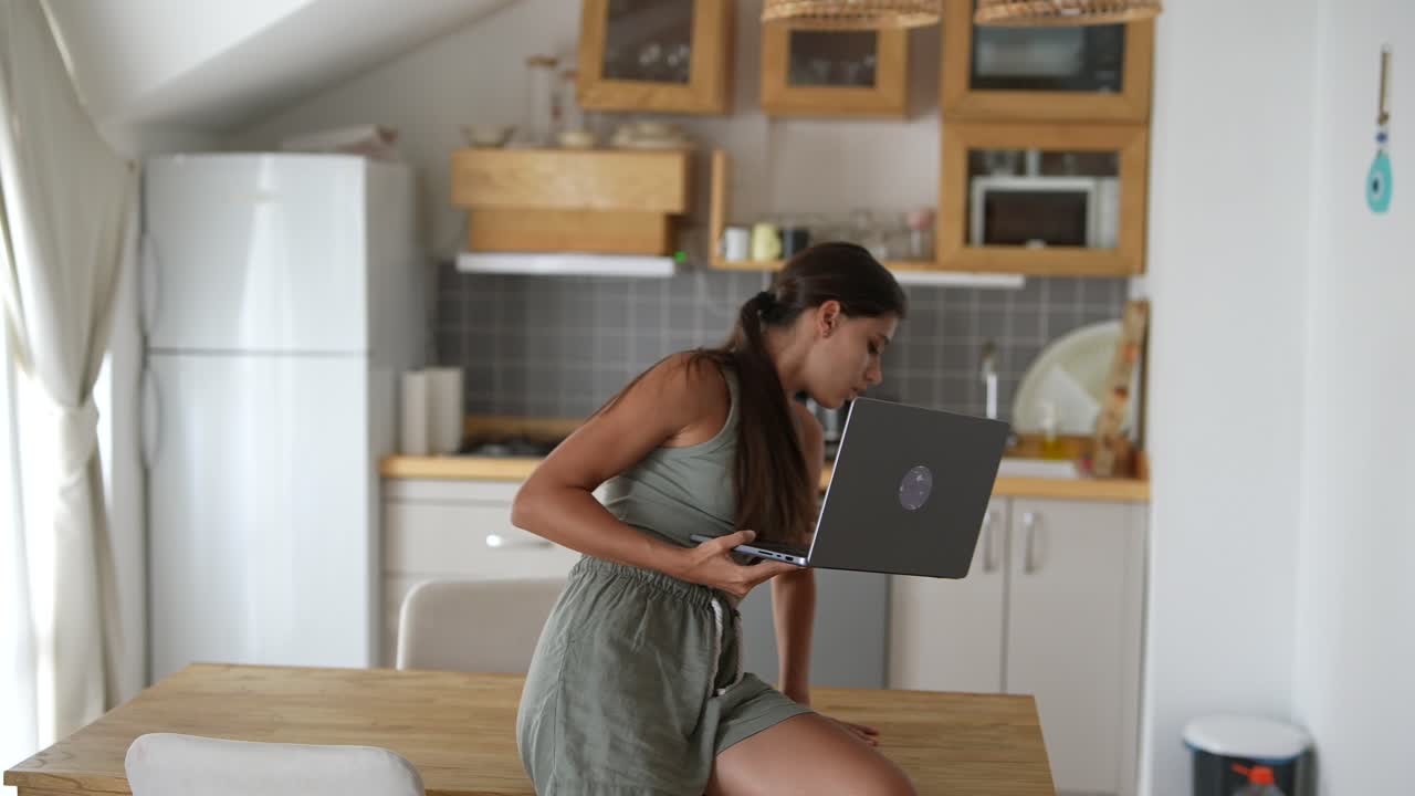 Young Woman Working on Laptop in Kitchen