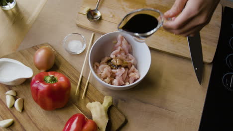 preparing chicken with soy sauce and fresh ingredients