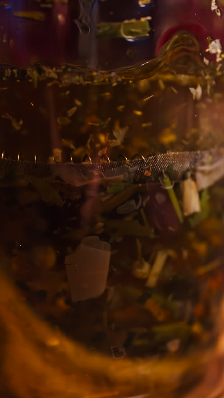 Close up of a woman pressing down the tea leaves with the help of a French press. Vertical