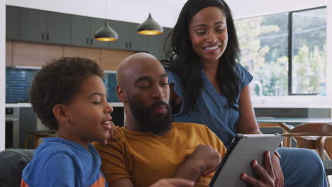 Afroamerikanische-Familie-Mit-Sohn,-Der-Zu-Hause-Auf-Dem-Sofa-Sitzt-Und-Ein-Digitales-Tablet-Nutzt