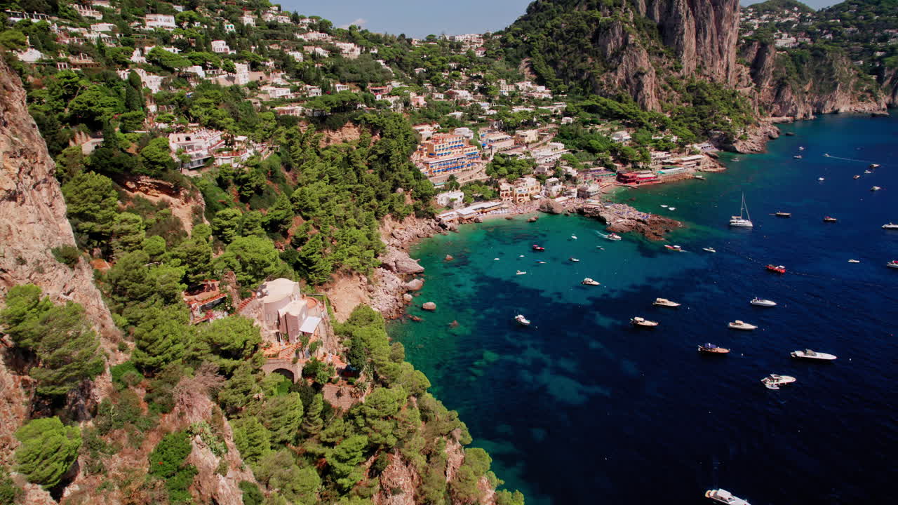una toma aérea épica que se acerca a las playas de marina piccola más allá de los impresionantes acantilados de capri, una isla famosa que es un popular destino de vacaciones de lujo en italia a lo largo de la costa de amalfi