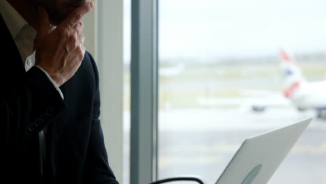 businessman looking at laptop at airport