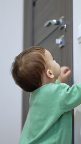 nice little kid switches off the light in the room. surprised toddler looks around the dark room. vertical video