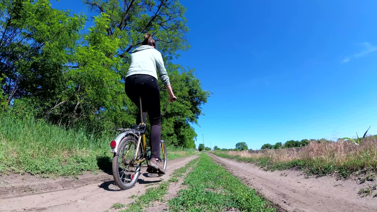 마을 의 시골 도로 를 따라 빈티지 자전거 를 타고 있는 젊은 여자