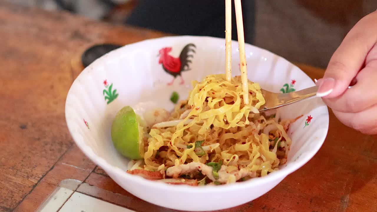 Mixing noodles with chopsticks and spoon