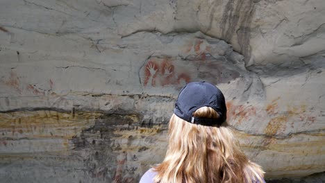 women immersing herself in the spectacular display of aboriginal rock art created on ancient cave walls of australia