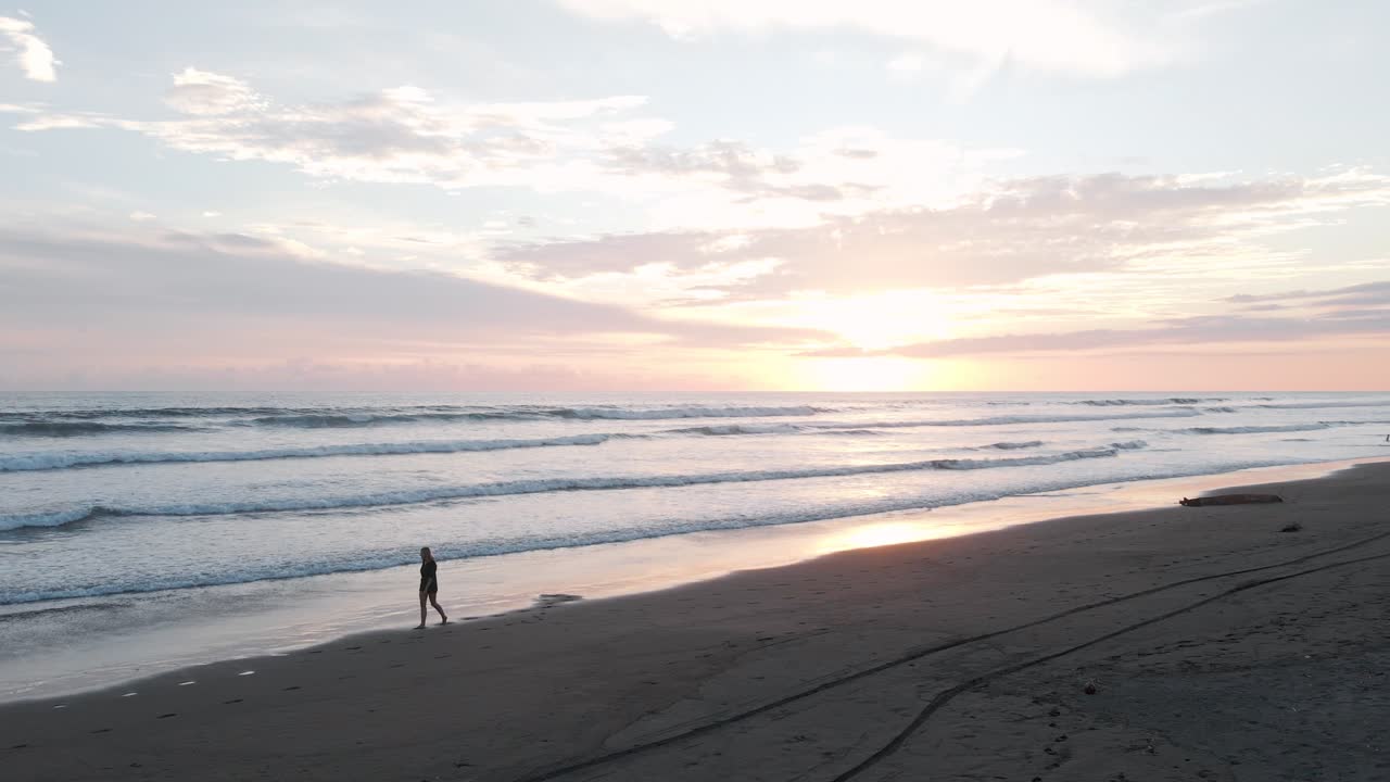 Woman walking along playa Bandera during a beautiful vibrant sunset in Puntarenas, Costa Rica