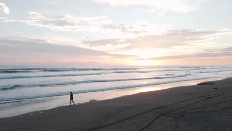 woman walking along playa bandera during a beautiful vibrant sunset in puntarenas, costa rica