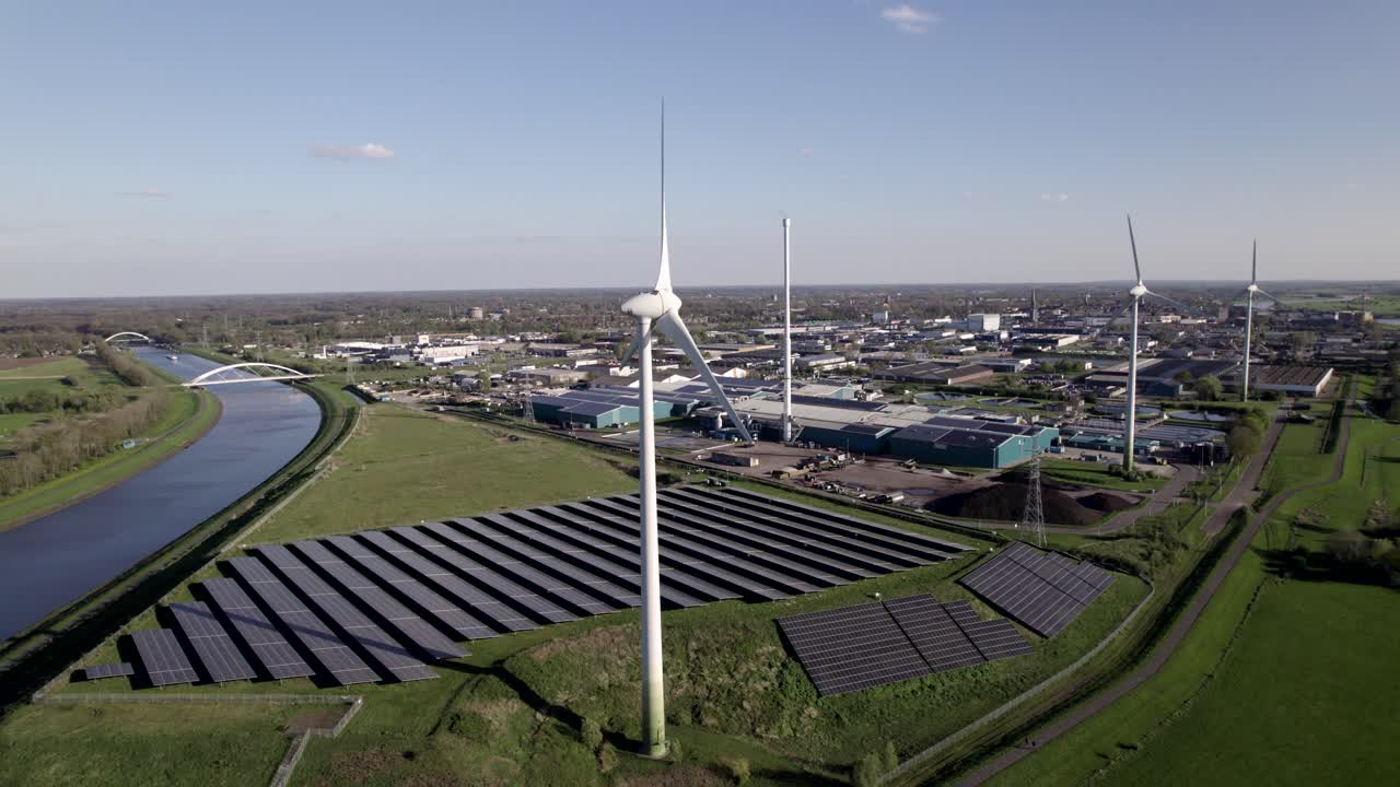 Clean energy wind turbines and solar panels hub in The Netherlands slow aerial pan on a sunny day