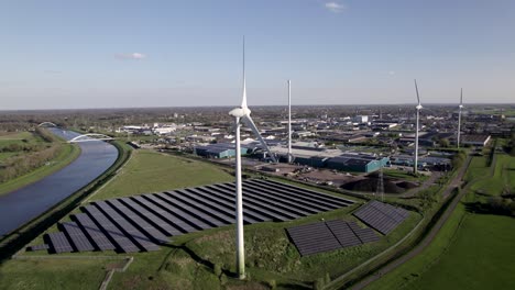 Turbinas-Eólicas-De-Energía-Limpia-Y-Centro-De-Paneles-Solares-En-Los-Países-Bajos-Lenta-Panorámica-Aérea-En-Un-Día-Soleado